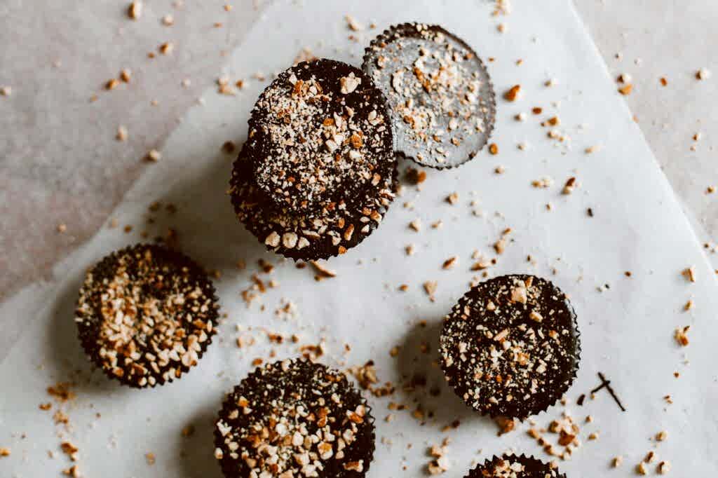 Top view of dark chocolate bites sprinkled with almonds on parchment paper.